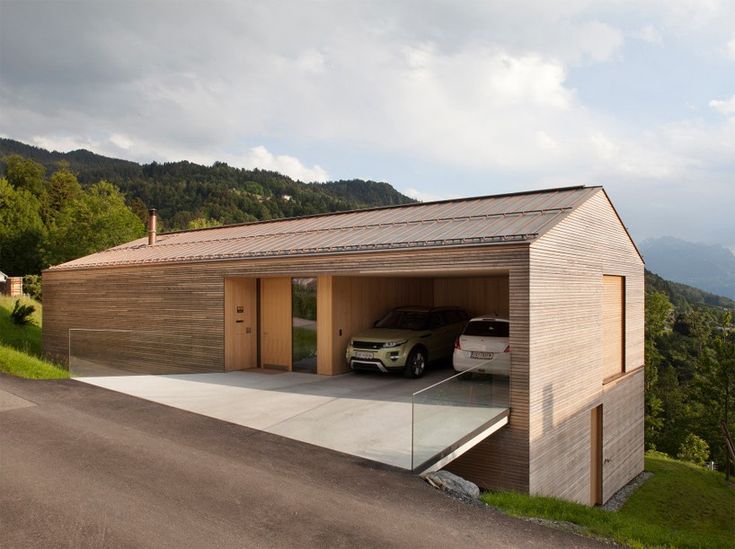 a car is parked in the garage of a house on top of a hill with mountains in the background