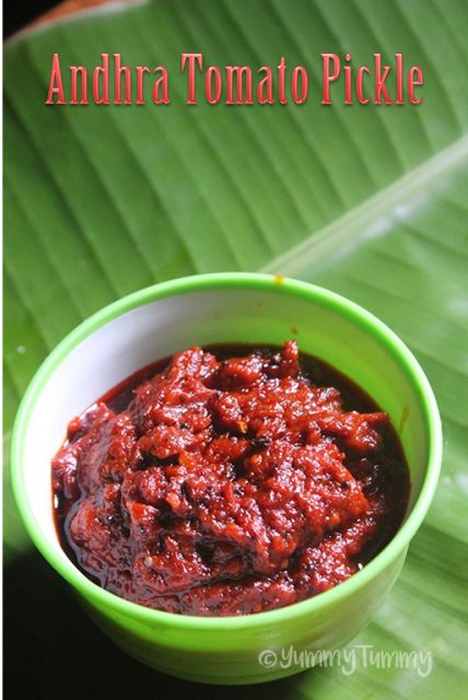 a green bowl filled with red sauce on top of a leafy green tablecloth