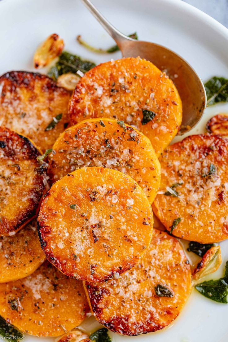 a white plate topped with sliced oranges covered in parmesan cheese and herbs