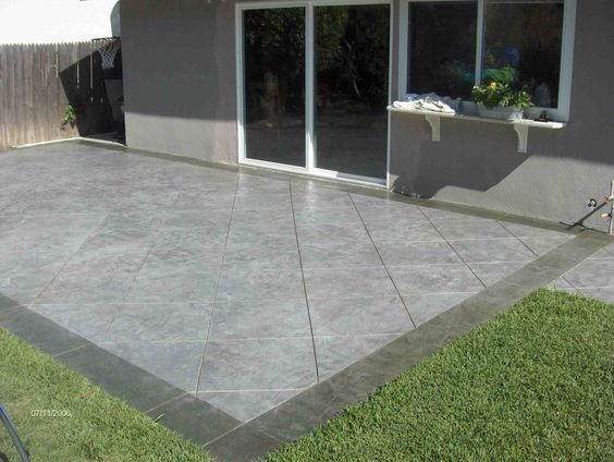 a concrete patio in front of a house with sliding glass doors on the outside side