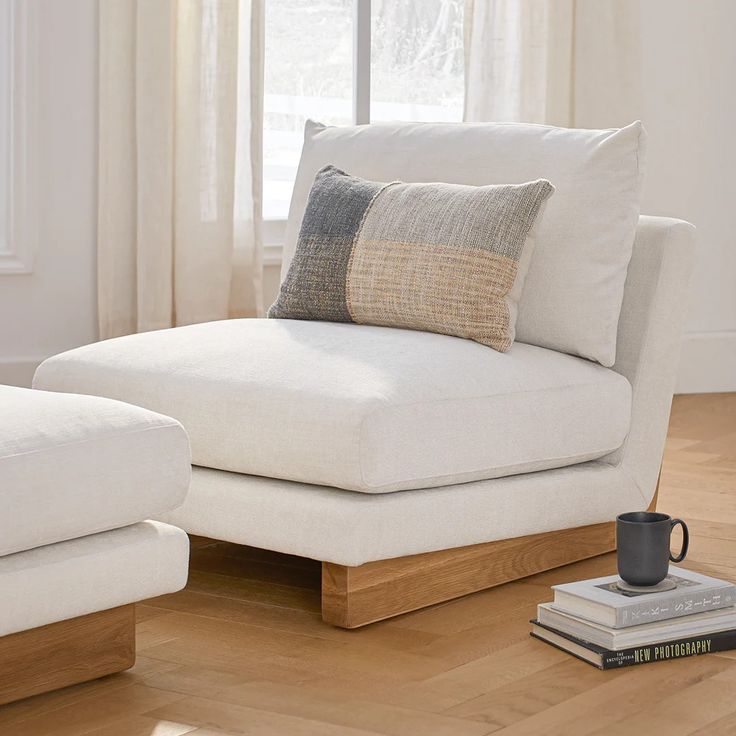 a living room with two white couches and a coffee cup on the floor next to each other