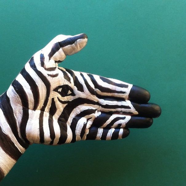 a zebra's hand is painted with black and white stripes on green wallpaper