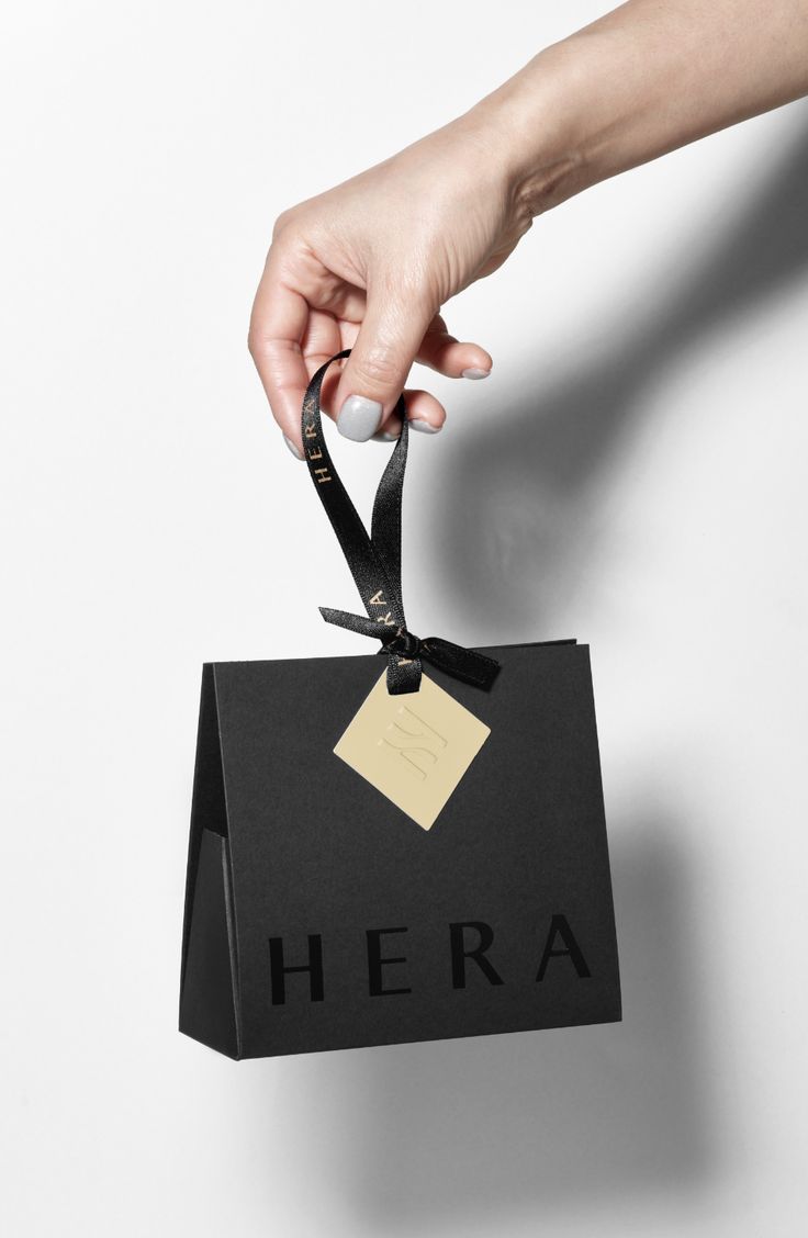 a hand holding a black bag with a tag on it that says hera hanging from the side