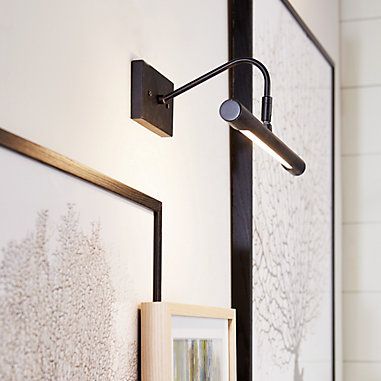 a wall mounted light next to two framed pictures