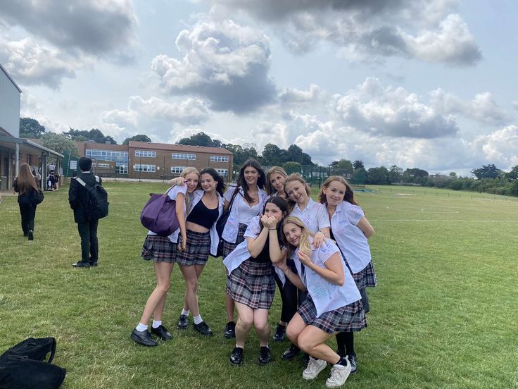 a group of young women standing next to each other on top of a lush green field