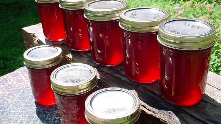 many jars are lined up on a picnic table