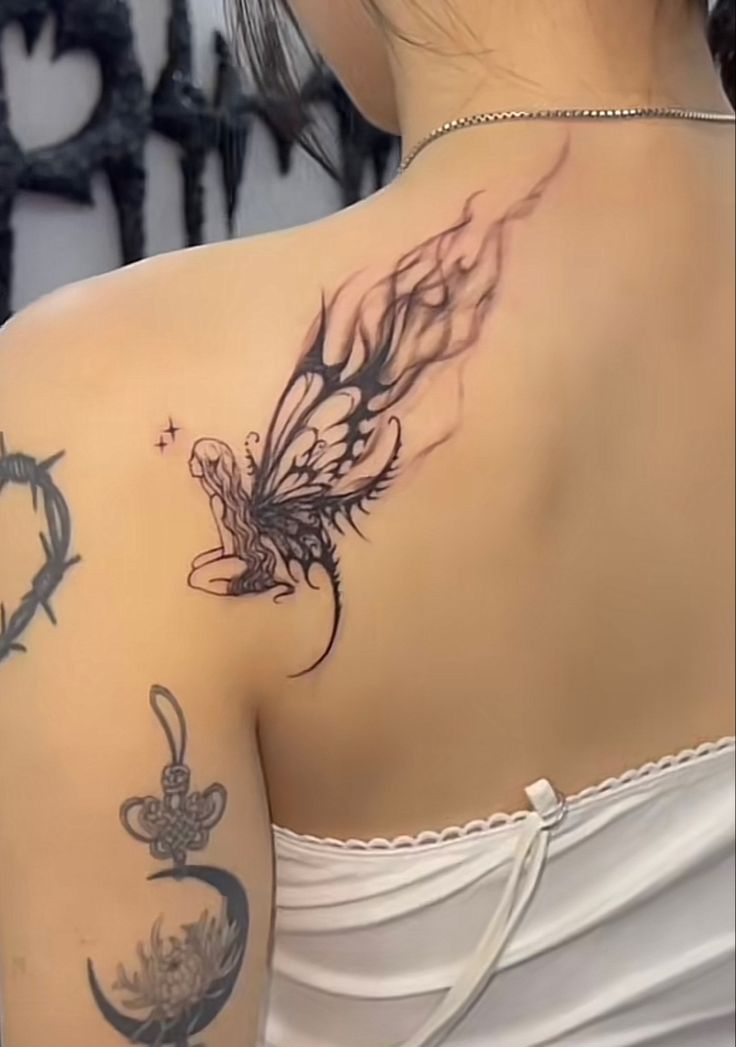 the back of a woman's shoulder with tattoos on it