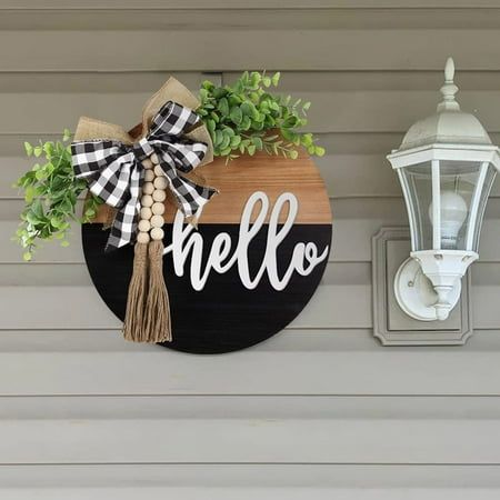 a wooden sign that says hello hanging on the side of a wall next to a lamp