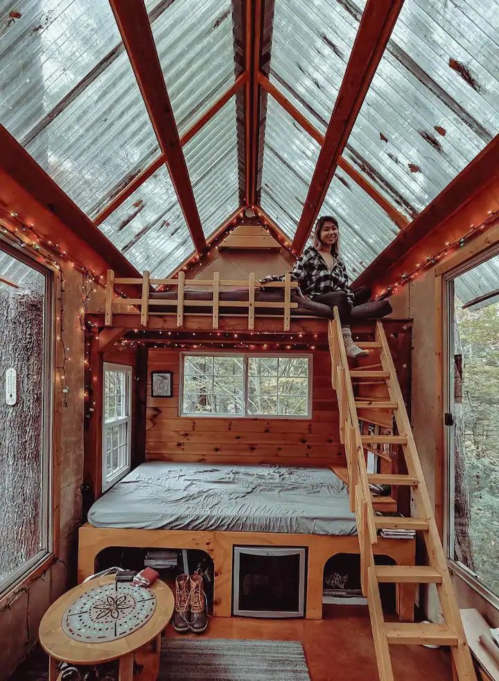 a person sitting on top of a bunk bed in a room filled with windows and lights