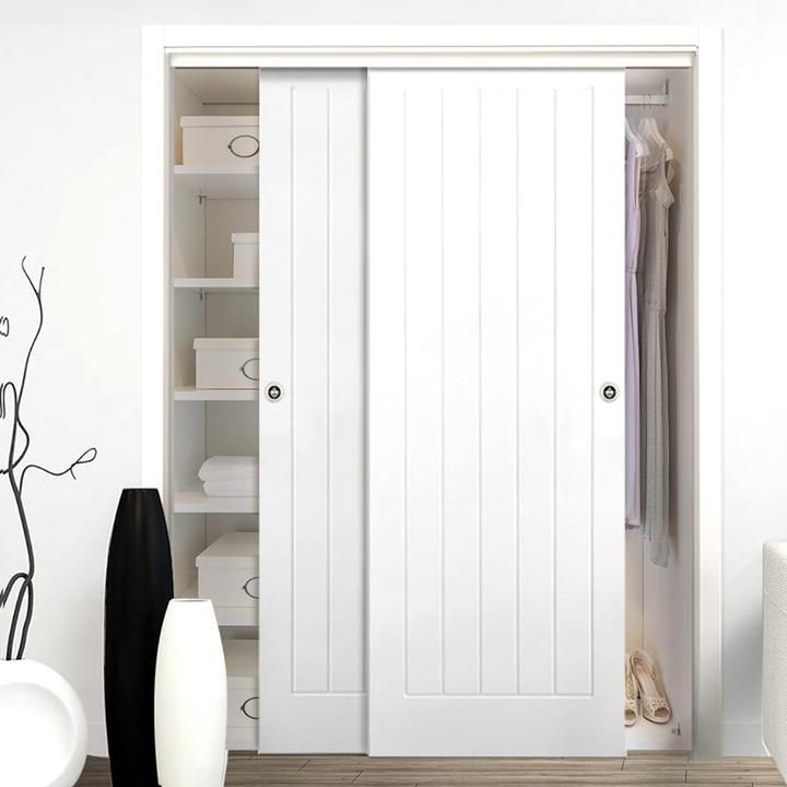 a white closet with two doors and some black vases on the floor next to it