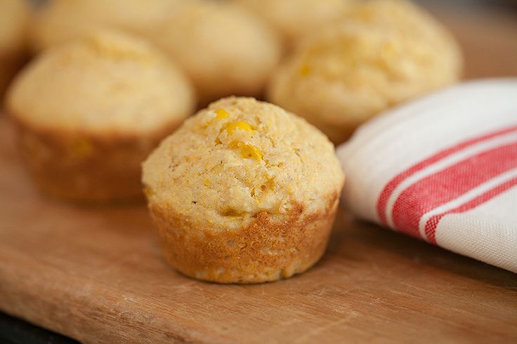 a muffin sitting on top of a wooden table next to a red and white towel