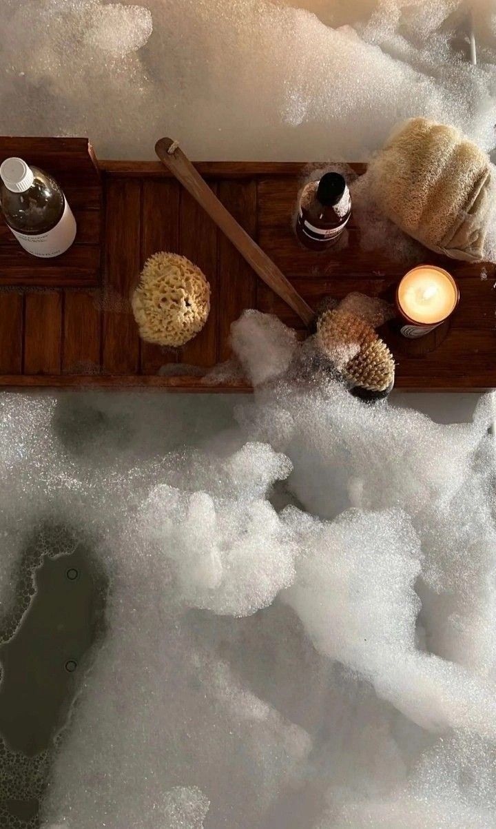 an aerial view of a bathtub with soap, candles and seashells