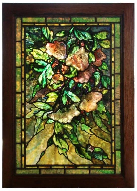 a stained glass window with flowers and leaves on it's side, in a wooden frame