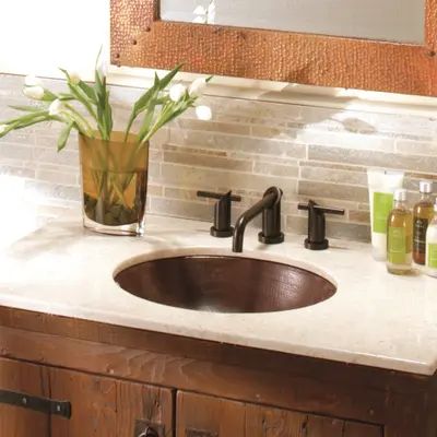 a bathroom sink sitting under a mirror next to a wooden cabinet with two glasses on it