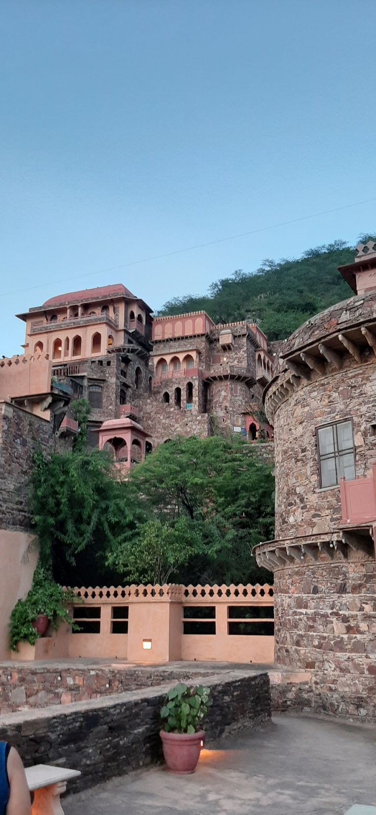 a castle like building sitting on top of a lush green hillside