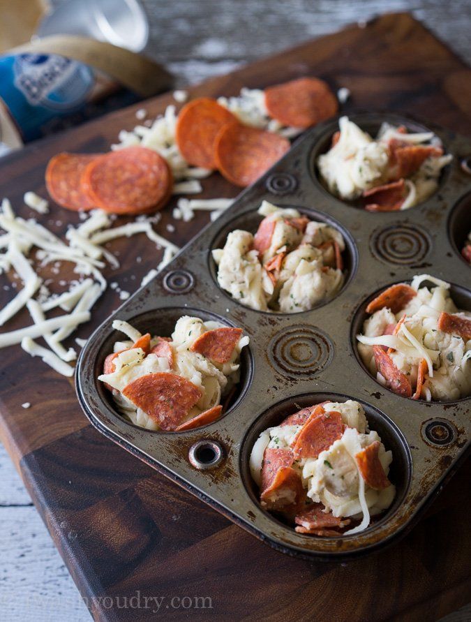 several muffin tins filled with different types of food on a wooden cutting board