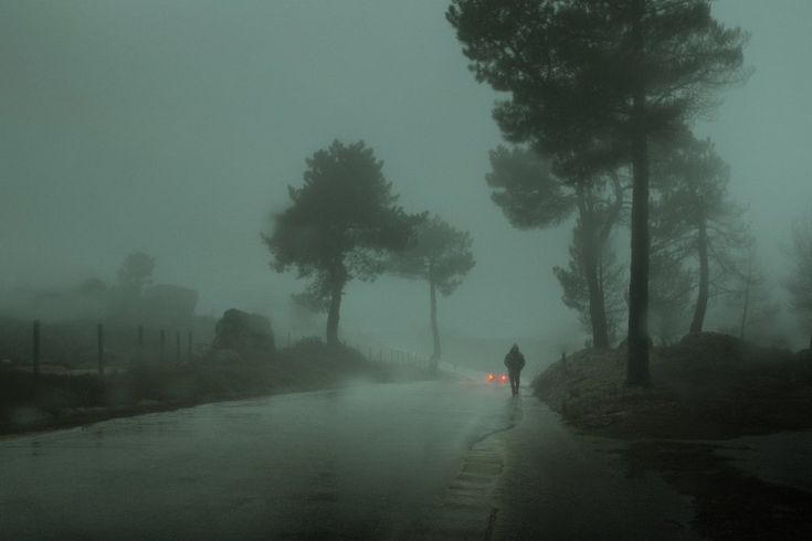 a person is walking down the road in the rain