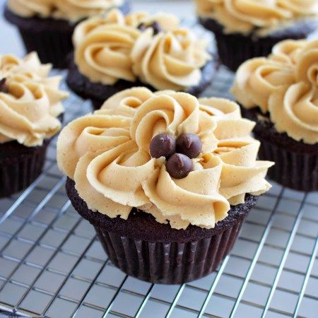 several cupcakes with frosting on a cooling rack