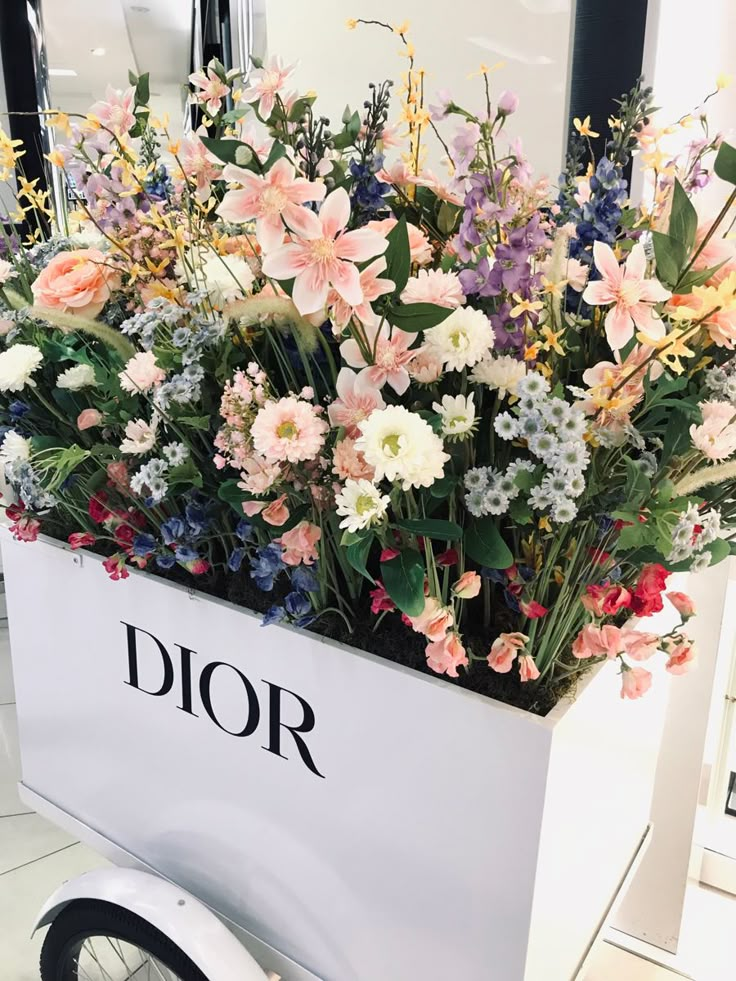 a flower arrangement sitting on top of a white box with the word dior in it