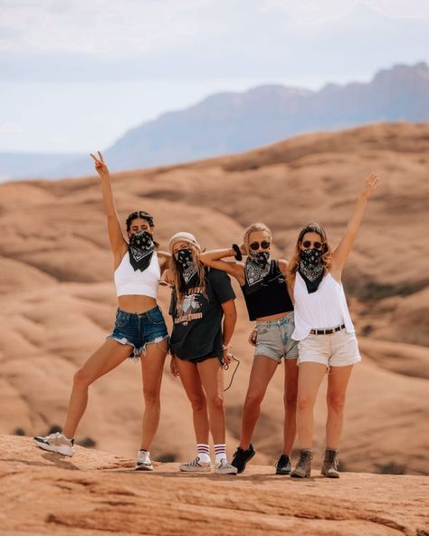 three women standing on top of a rock with their arms in the air and wearing bandanas