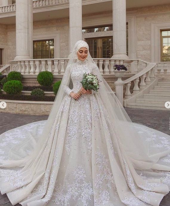 a woman wearing a wedding gown and veil standing in front of a large white building