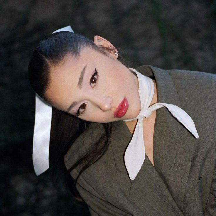 a woman with long black hair wearing a white bow tie