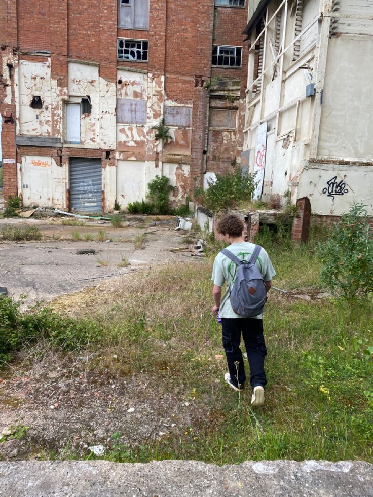 a young boy with a backpack walking through an abandoned building