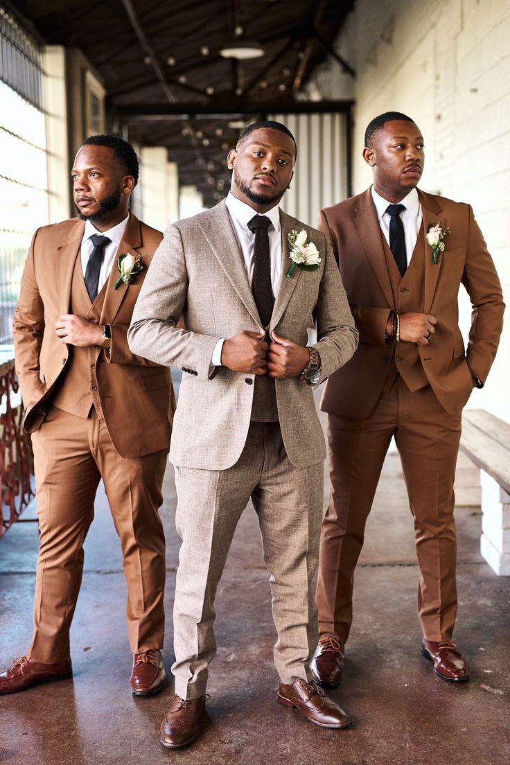 three men in suits standing next to each other wearing ties and vests with flowers on their lapels