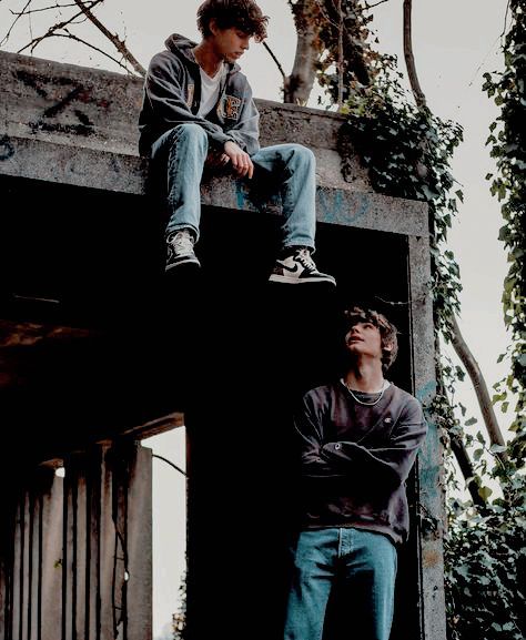 two young men sitting on top of a building