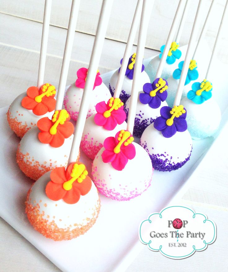 cake pops with colorful frosting and flower decorations on a white platter, ready to be eaten