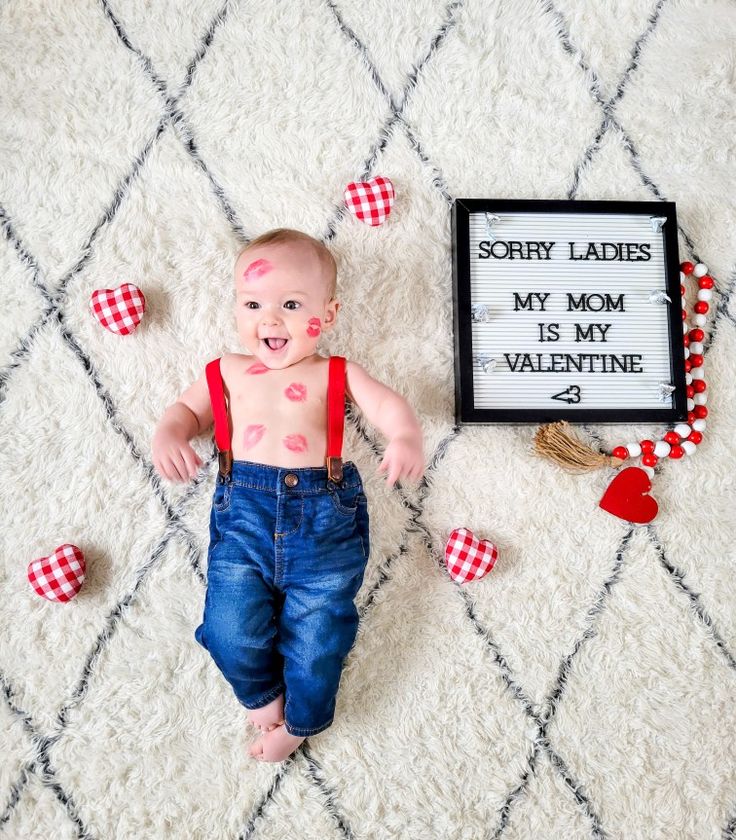 a baby laying on the floor next to a sign that says sorry ladies my mom is my valentine