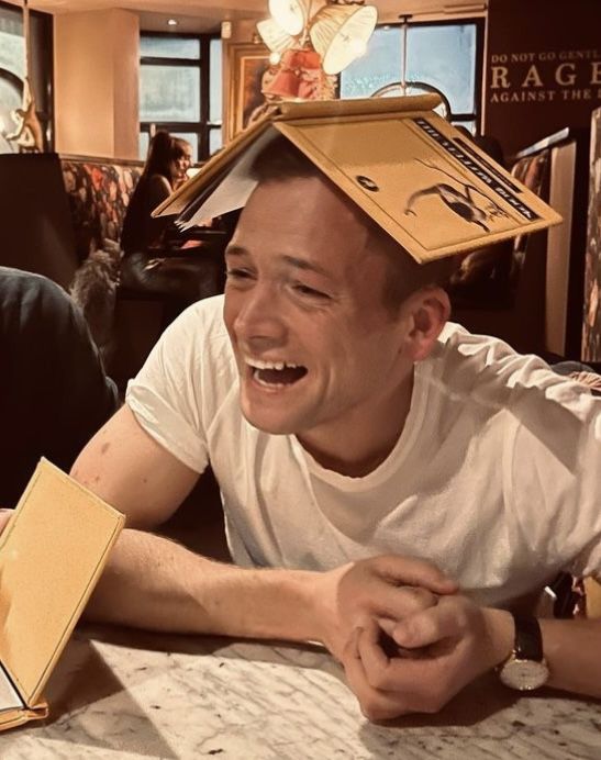 a man sitting at a table with a cardboard box on his head in front of him