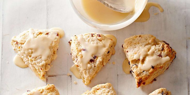 several scones with icing next to a cup of tea