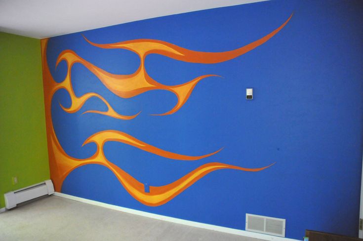 an empty room with blue walls and orange flames painted on the wall