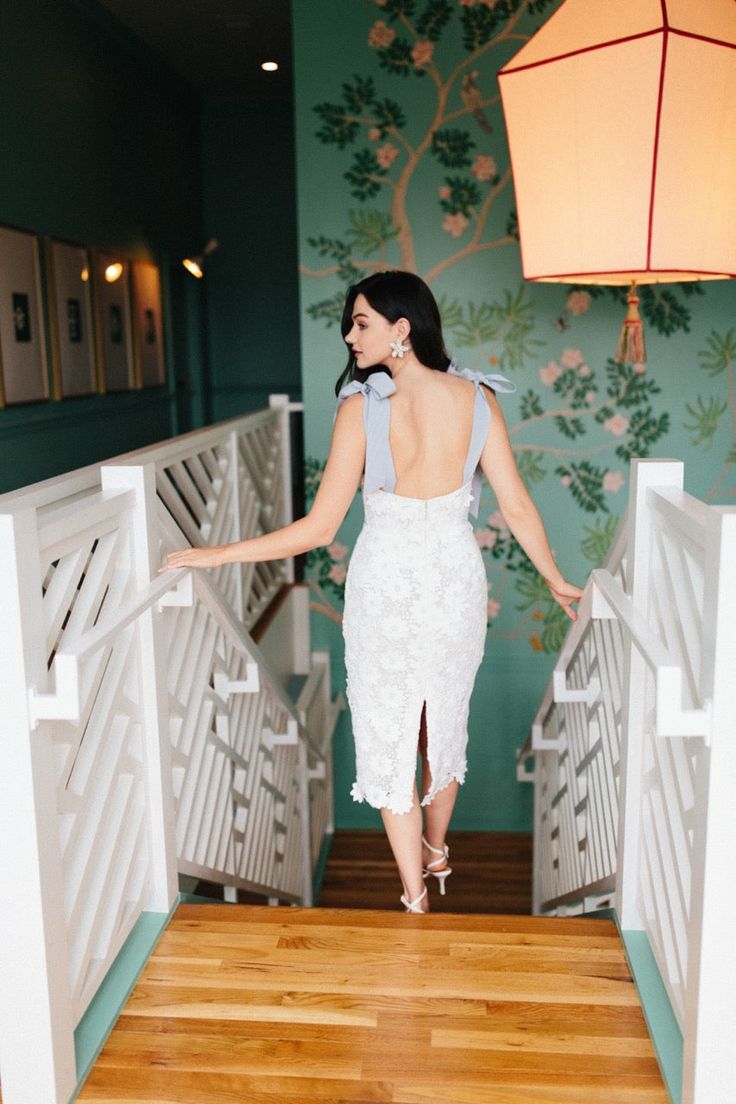 a woman in a white dress is walking down the stairs