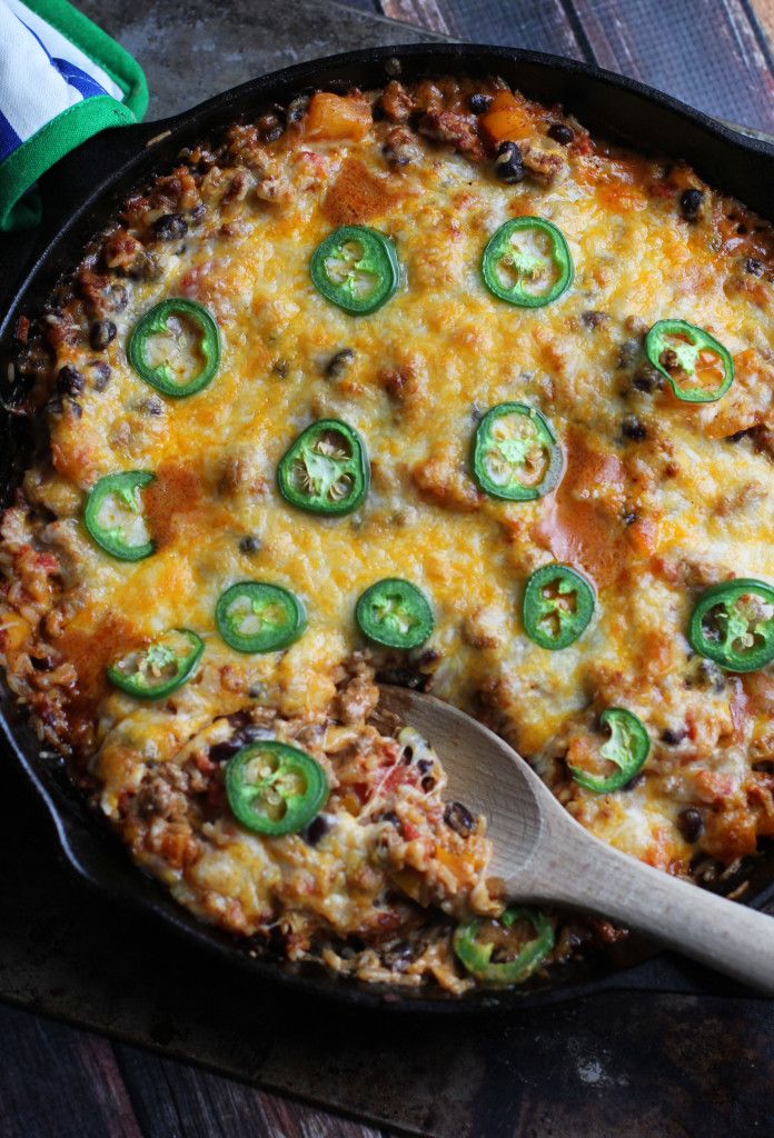 a casserole with green peppers and cheese in a cast iron skillet on a wooden table