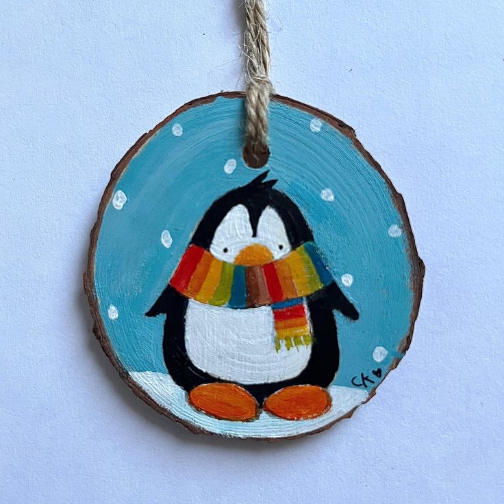 a wooden ornament with a penguin painted on it