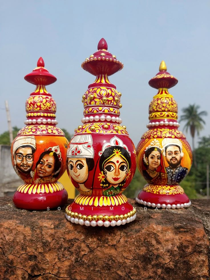 three colorfully painted vases sitting on top of a rock