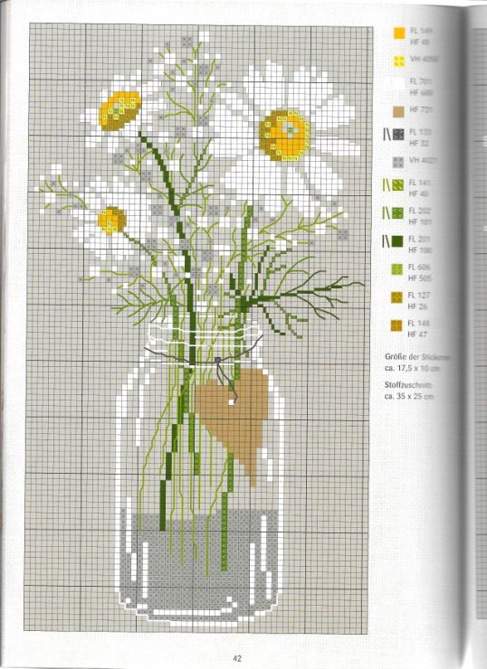 a cross stitch book with a vase filled with daisies on top of a table