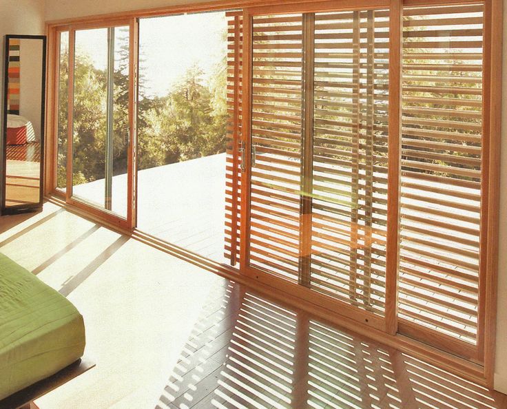 an open window with wooden slats on the outside, and sliding glass doors in the inside