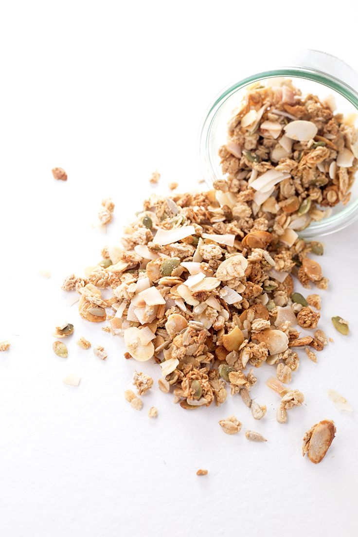 granola in a small glass jar on a white surface next to it's contents