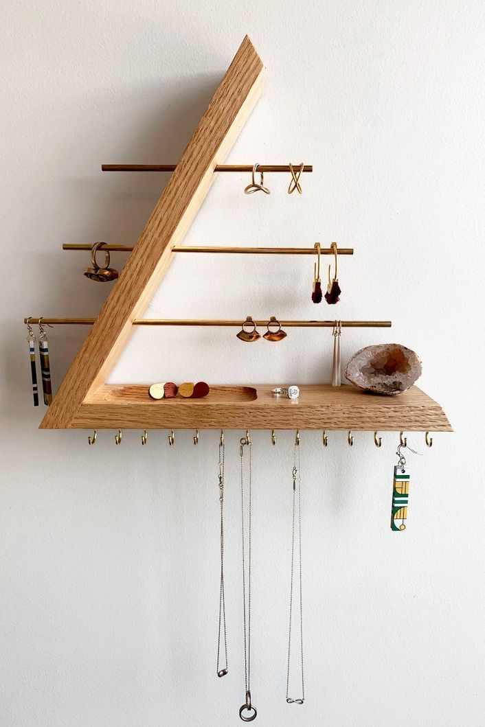 a wooden shelf with several pairs of earrings hanging from it's sides and hooks attached to the wall