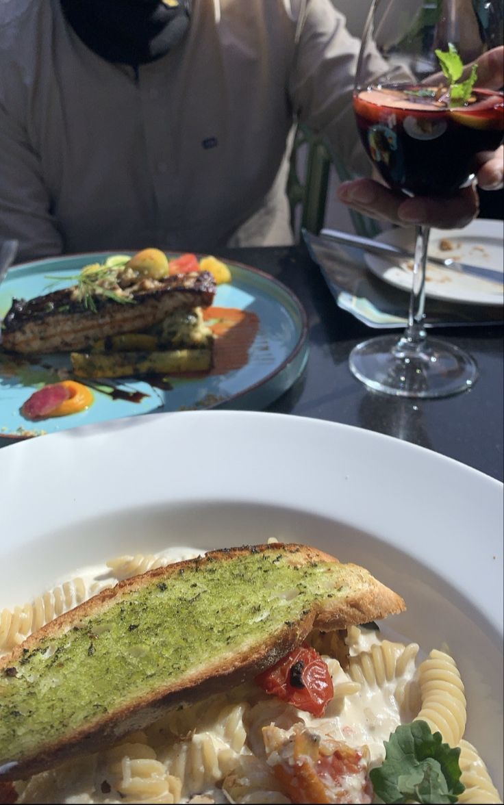 a man sitting at a table in front of a plate of food with pasta and vegetables