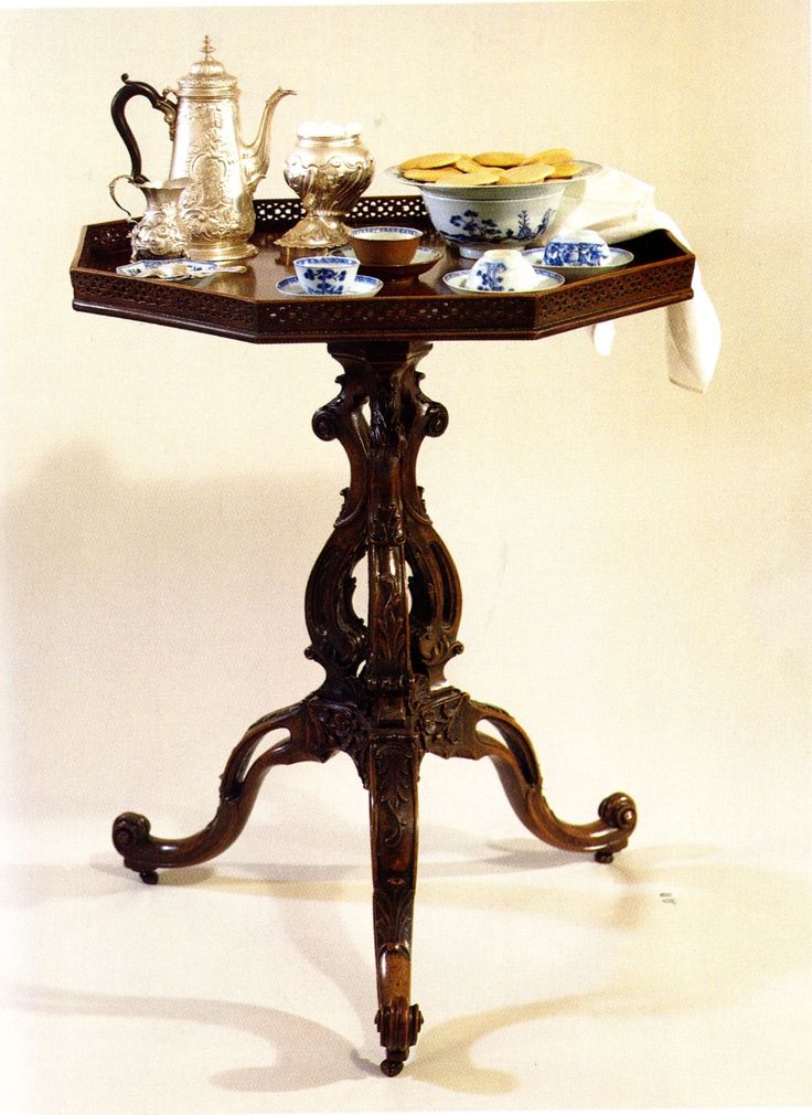 an ornate table with tea and coffee cups on it is shown in front of a white background