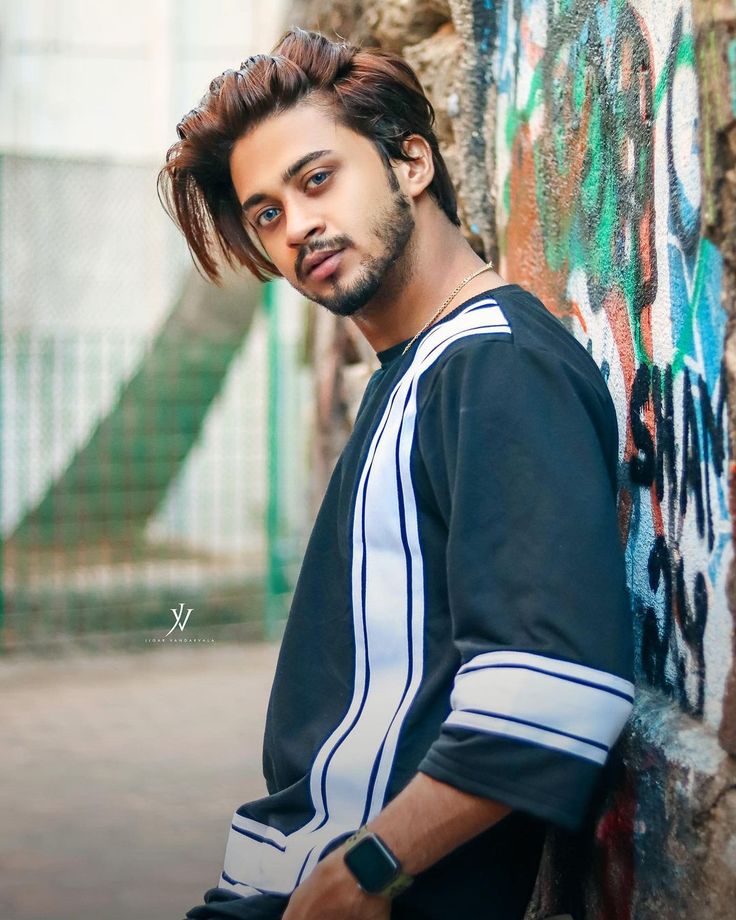 a young man leaning against a wall with graffiti on it's walls and looking at the camera