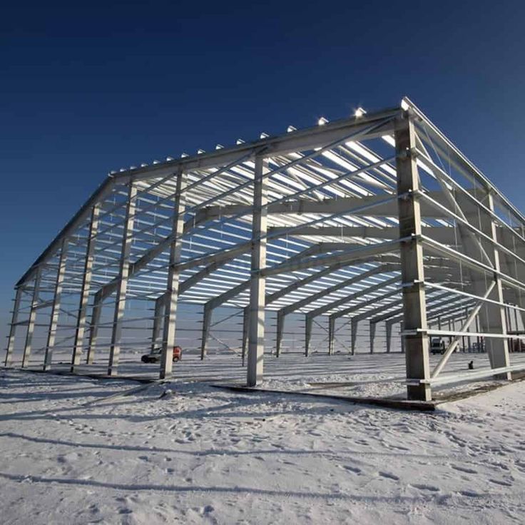 a large metal structure sitting on top of a snow covered field in front of a blue sky