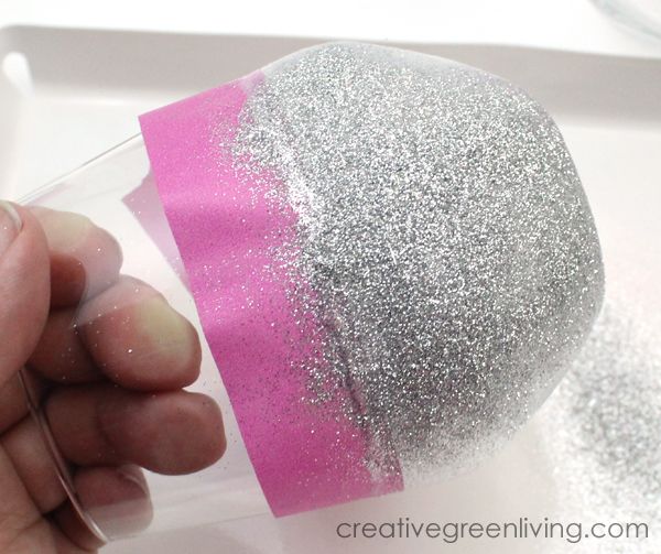 a hand is holding a cup with glitter on it and pink paper in the bottom