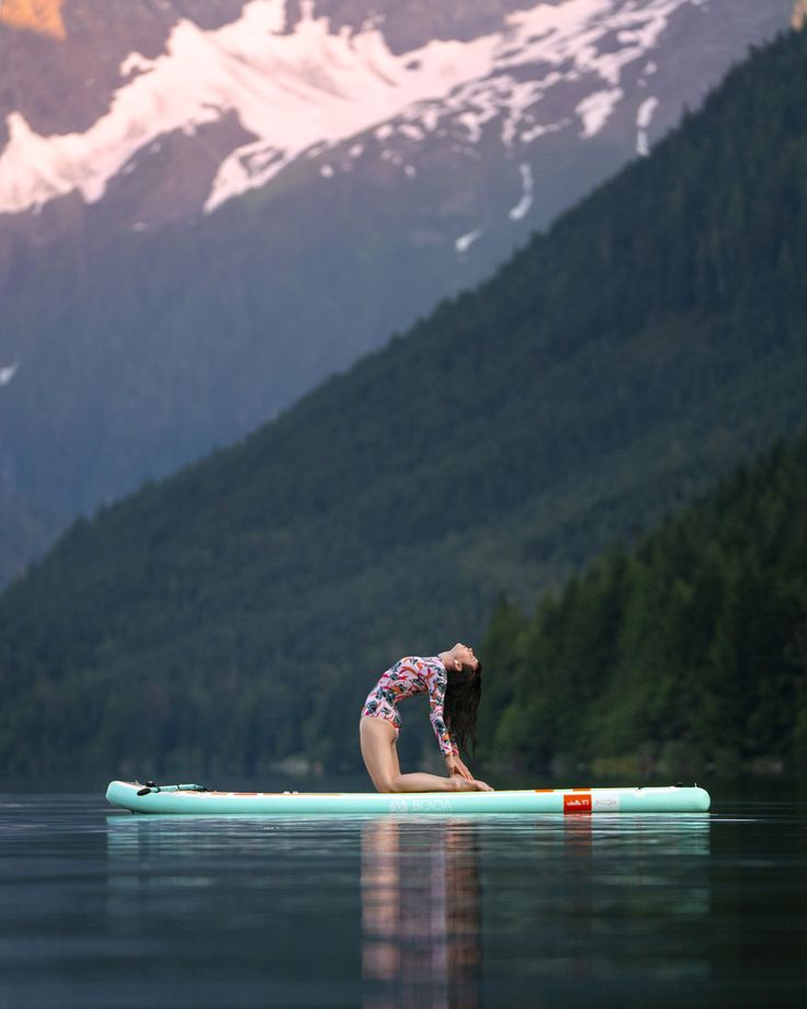 a woman sitting on top of a surfboard in the middle of a body of water