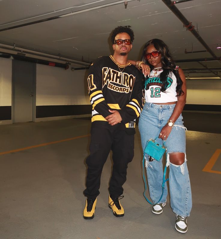 two people standing next to each other in an empty parking garage with one person wearing sunglasses and the other holding a purse