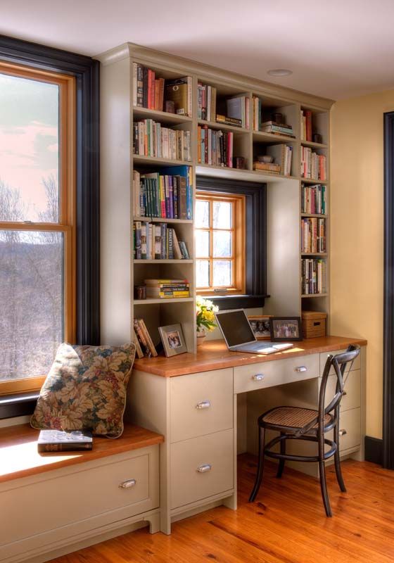 a home office with bookshelves, desk and chair in front of a window